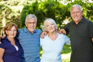 Group of four smiling senior friends standing outdoors in a park