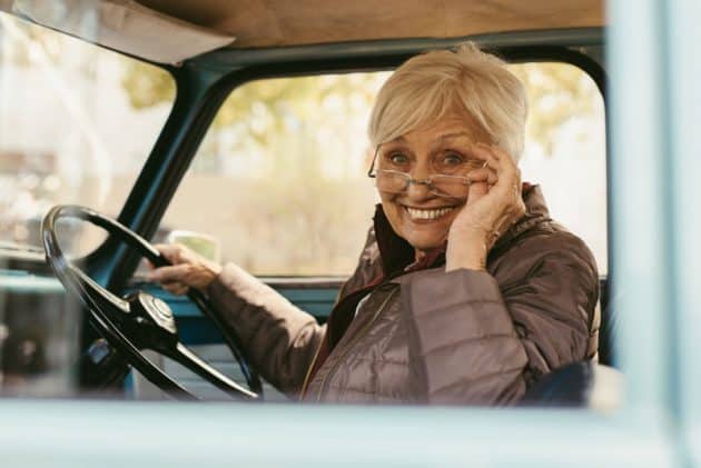 An older adult behind the wheel of her car.