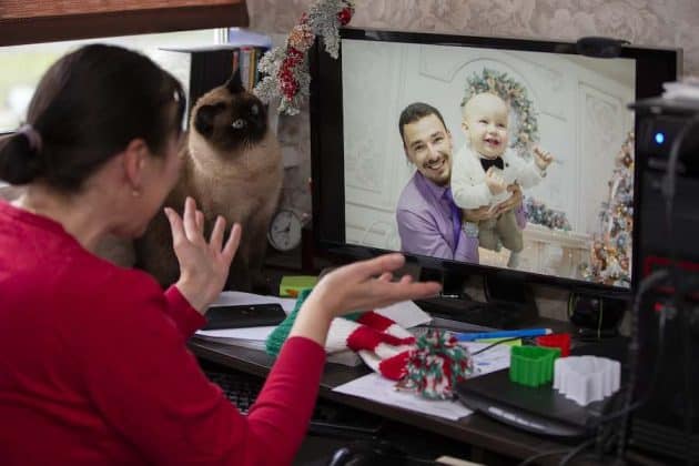 An older woman on a video call with her son and grandson during the holidays.