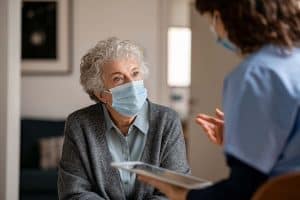 A senior woman talking with a healthcare professional about how she can protect herself from the flu.