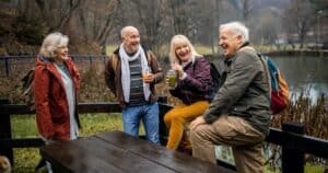 Four seniors laughing by a lake