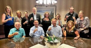 Group of Silver Maples staff smiling and holding glasses in a celebratory toast around a table