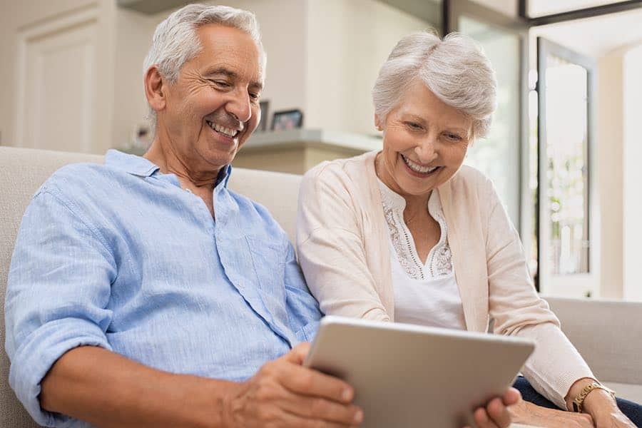 An older adult couple video chatting with friends to stay connected during social distancing.