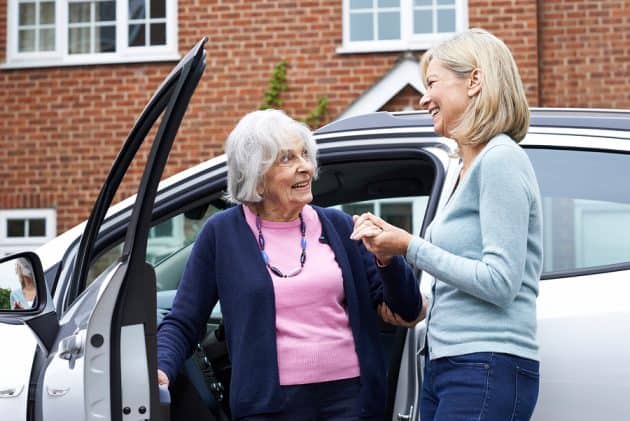 Adult daughter helps her mother get out of the car