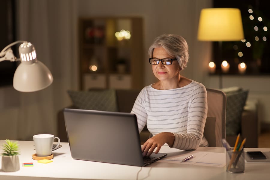 A senior citizen woman participating in an online volunteer opportunity from her own home.