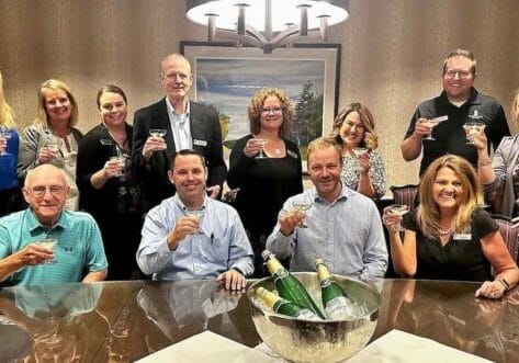 Group of Silver Maples staff smiling and holding glasses in a celebratory toast around a table