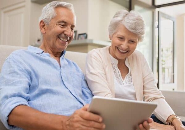 An older adult couple video chatting with friends to stay connected during social distancing.