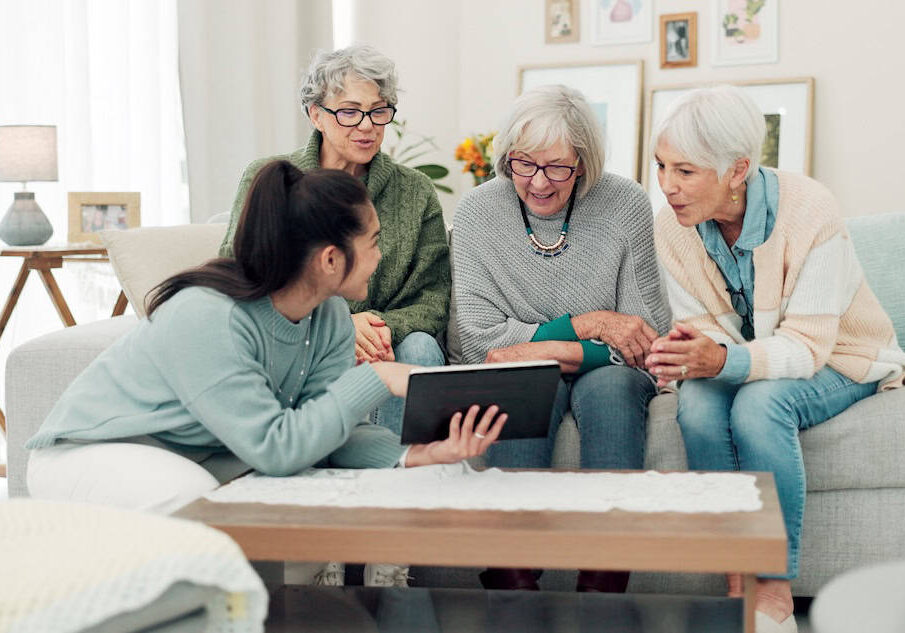 Tablet, friends and senior women on sofa online for social media, streaming movies and internet search. Retirement home, social reunion and caregiver on digital tech for learning, teaching and help