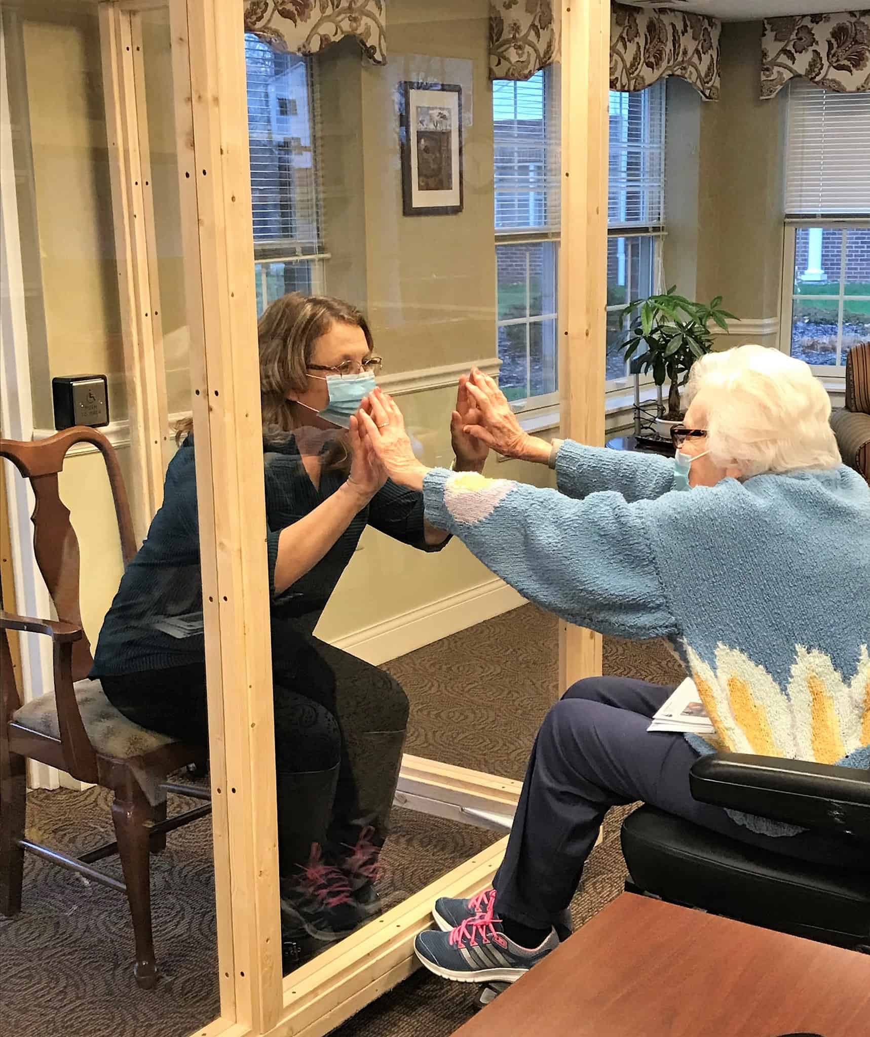 Silver Maples resident and family member having a safe visit with our new plexiglass Visiting Booth.